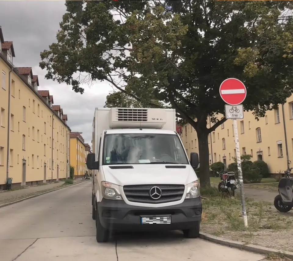 Straße mit Einbahnstraßen-Schild und entgegenkommendem Transporter
